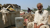 Rustam Khan sits in front of his destroyed house